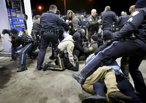 Police try to control a scuffle on the lot of a gas station following a shooting in which a black teenager was killed. Picture: AP