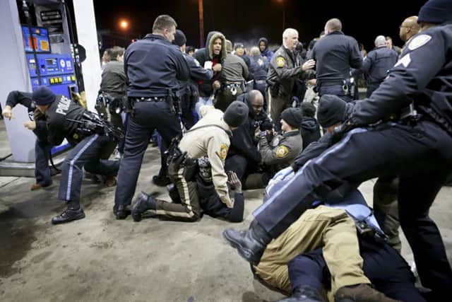 Police try to control a scuffle on the lot of a gas station following a shooting in which a black teenager was killed. Picture: AP