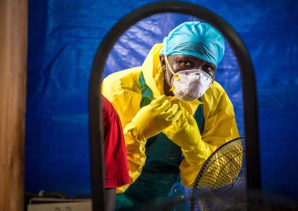 A healthcare worker dons protective gear before entering a treatment centre in Freetown in October. Picture: AP