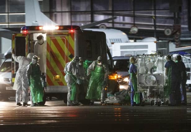 The healthcare worker (C) is walked from an ambulance and put into a quarantine tent trolley. Picture: Getty