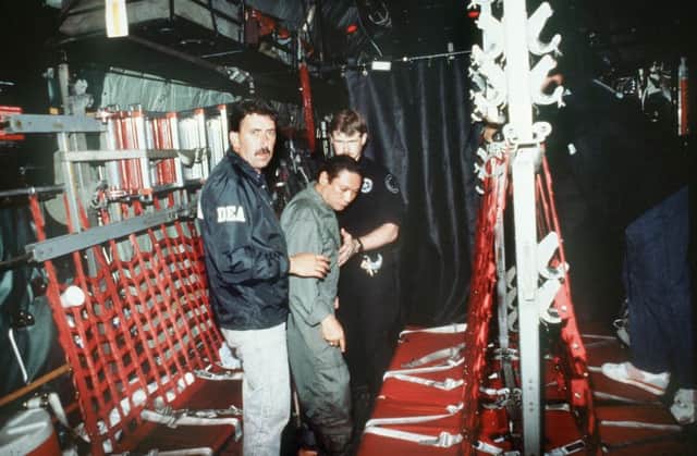 Panamas General Manuel Noriega is escorted by US officials on a flight to Florida in 1990 to face drug charges. Picture: Getty