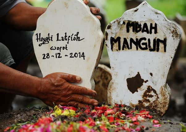 A caretaker tends the grave of Hayati Lutfiah Hamid, the first identified victim of the AirAsia flight QZ8501 crash. Picture: Getty