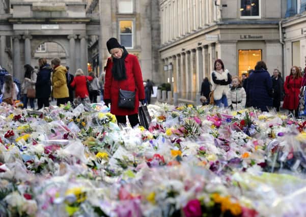 Mourners survey floral tributes left outside GOMA for the victims of the bin lorry crash in Glasgow. Picture: John Devlin