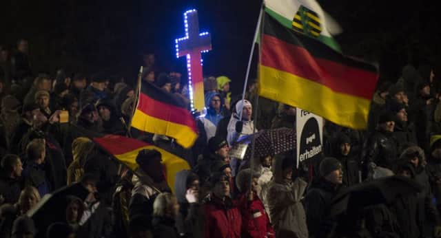 A Pegida demonstrator marches holding a cross in Germanys national colours during a rally in Dresden on Monday night. Picture: Getty
