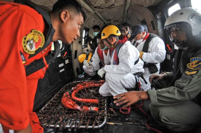 Rescuers in a helicopter swap information during the search for victims and wreckage. Picture: AP