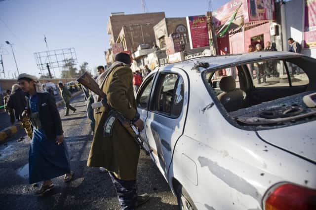 A policeman inspects a damaged vehicle at the scene of the car bombing outside the police academy in Sanaa. Picture: AP
