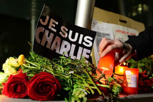 A man lights a candle next to a poster reading "Je suis Charlie" (I am Charlie). Picture: Getty