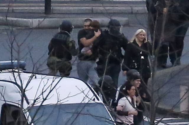 Man and child are helped out of kosher supermarket after police launch assault on hostage takers in Paris. Picture: Getty