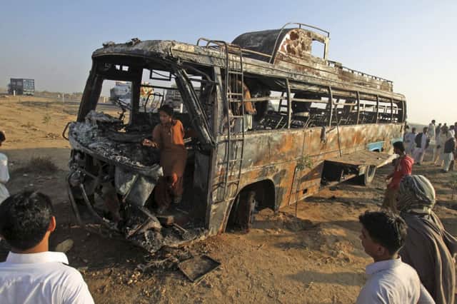 Onlookers stare in disbelief at the seared remains of the bus after it hit an oil tanker travelling on the wrong side of the road, leaving just a few passengers alive. Picture: AP