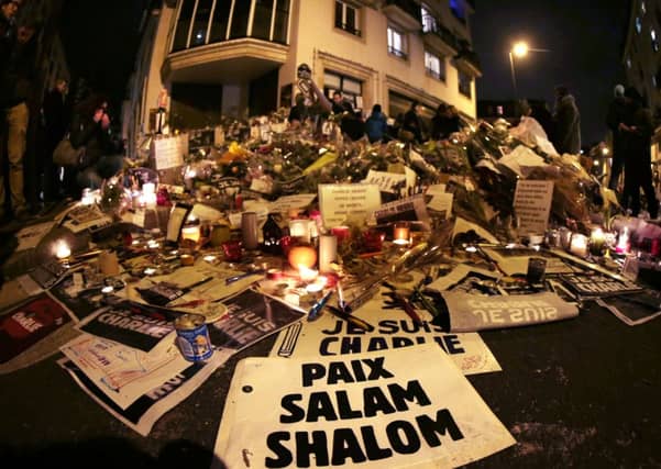 A sign reading Peace, Salam, Shalom lies at a makeshift memorial near the headquarters of the French satirical weekly Charlie Hebdo on Monday. Picture: Getty