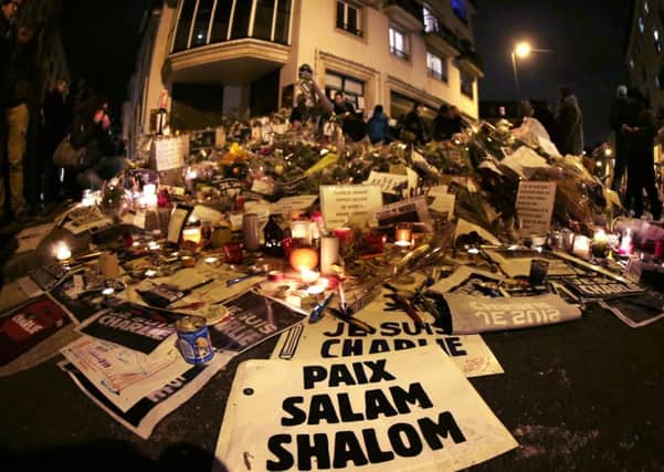 A sign reading Peace, Salam, Shalom lies at a makeshift memorial near the headquarters of the French satirical weekly Charlie Hebdo on Monday. Picture: Getty