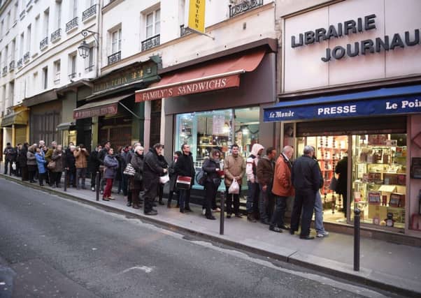 People wait outside a newsagents in Paris as the latest edition of French satirical magazine Charlie Hebdo goes on sale. Picture: Getty