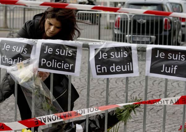 A woman puts up a sign reading "I Am Charlie", "I Am A Police Officer", "I Am Mourning", and "I Am Jewish". Picture: AP