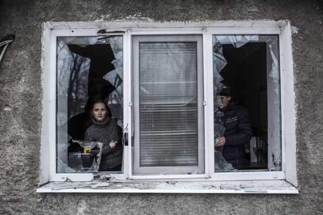 A Ukrainian woman looks through a broken window after it was hit by artillery in the Voroshilovsky area of Donetsk. Picture: AP