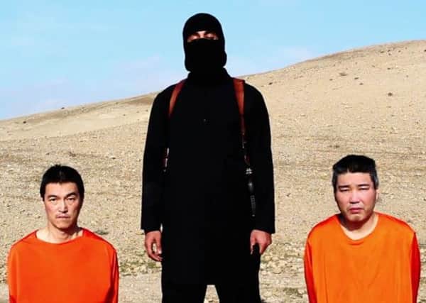Two Japanese hostages - Kenji Goto Jogo, left, and Haruna Yukawa, right - are pictured with the IS militant known as Jihadi John. Picture: AP
