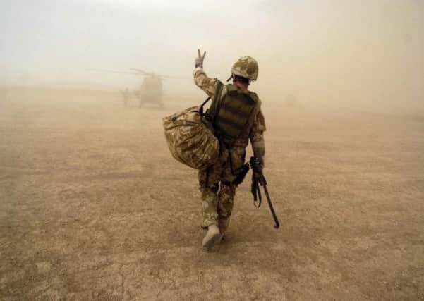 A soldier signals to a Lynx helicopter pilot in the murk of a Helmand dawn. Picture: TSPL