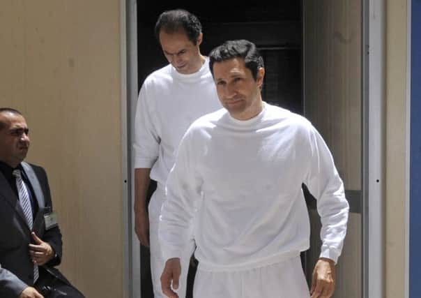 Mubarak brothers Gamal, left and Alaa walk out into the sun on leaving Tora prison.  Picture: AP