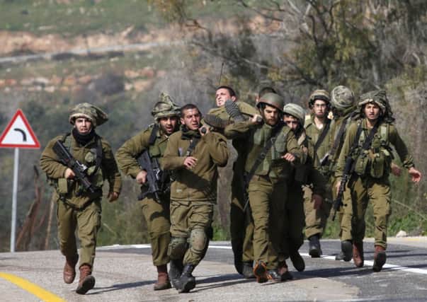 Israeli soldiers carry an injured comrade after an antitank missile hit an army vehicle on the border with Lebanon yesterday. Picture: Getty