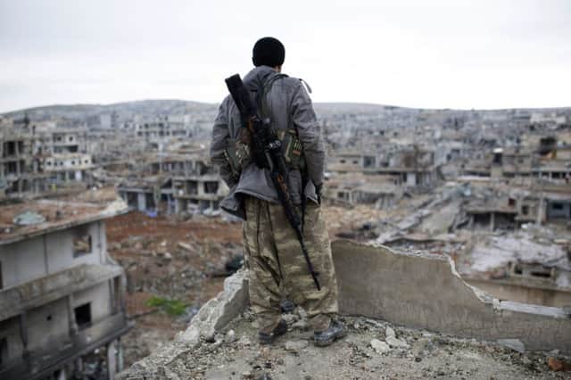 A Kurdish fighter surveys the ruins of Kobani, on the Turkish-Syrian border, after IS fighters were driven out last week. Picture: AP