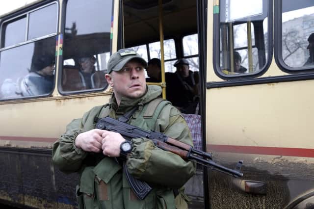 A soldier stands guard as people wait to leave the besieged Ukrainian town of Debaltseve. Picture: AP