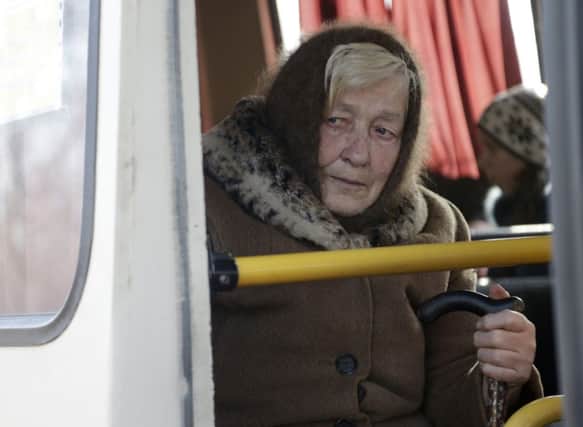 An elderly woman looks wistfully from a bus as she is evacuated from the village of Klynove. Picture: AP