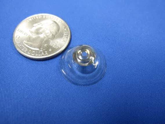 One of the  telescopic contact lenses next to a 25-cent coin. Picture: PA