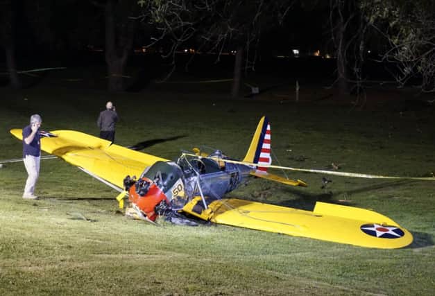 National Transportation Safety Board investigator Patrick Jones, left, stands by Harrison Ford's small plane. Picture: AP