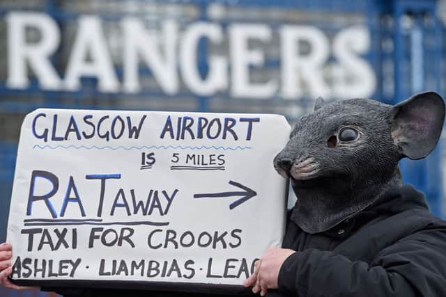 A Rangers fan wearing a rat mask holds up a sign outside Ibrox before the EGM. Picture: Getty