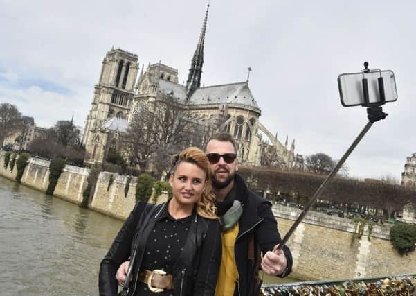 Tourists in Paris use a selfie stick near Notre Dame cathedral - but the National Gallery has banned the devices. Picture: Getty