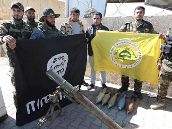 Shiite militiamen pose for a photo with their banner, right, and a captured IS flag, left, upside down, in Tikrit.  Picture: AP