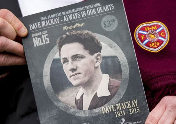 A Hearts fan holds Saturdays match programme, which remembers Dave Mackay. Picture: SNS
