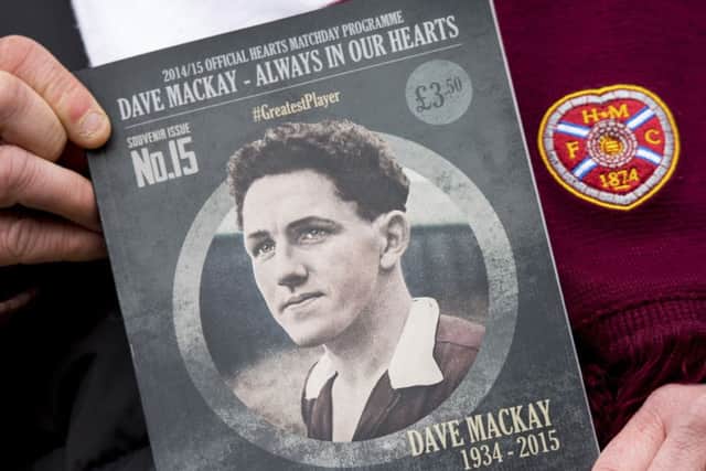 A Hearts fan holds Saturdays match programme, which remembers Dave Mackay. Picture: SNS