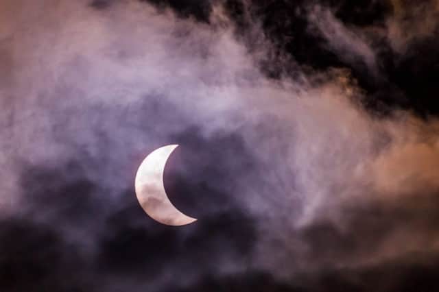 Glasgows grey skies meant the eclipse was visible only briefly during breaks in the cloud. Picture: SWNS