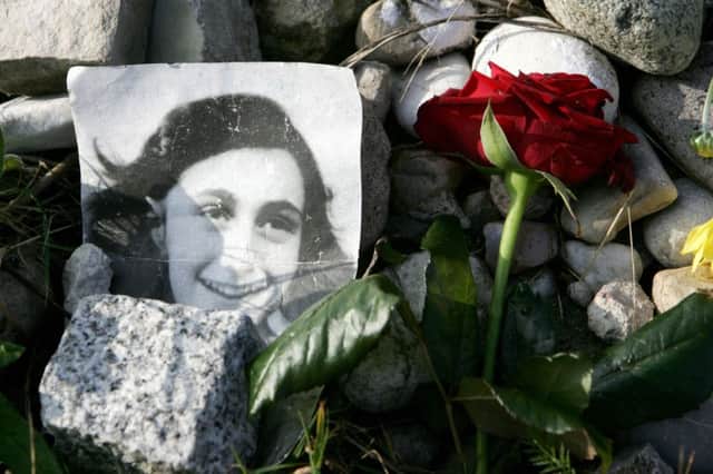 A picture of Anne Frank in front of the memorial stone for her and her sister Margot. Picture: Getty