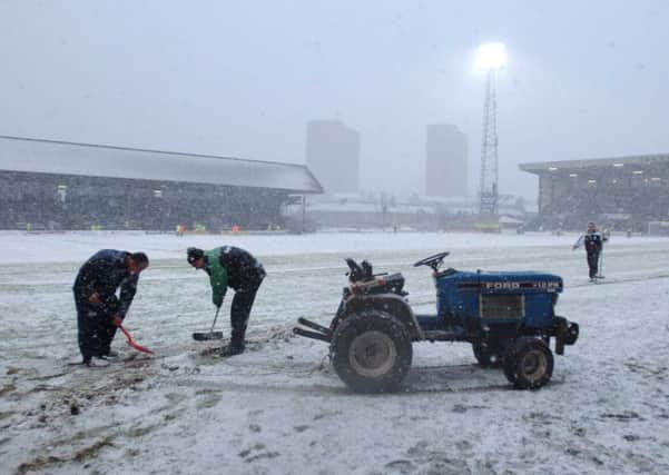 Snow is swept off the pitch at Dens Park before a scheduled fixture between Dundee and Hibernian is abandoned in 2003. Picture: Phil Wilkinson