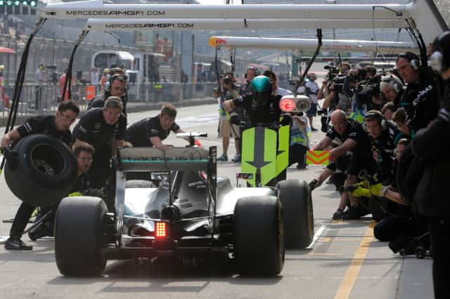 Mercedes crew members prepare to change Lewis Hamiltons tyres during practice yesterday. Picture: AP