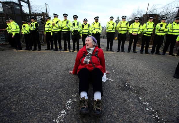 An demonstrator sits in the road to block the entrance to HM Naval Base Clyde, Faslane. Picture: PA