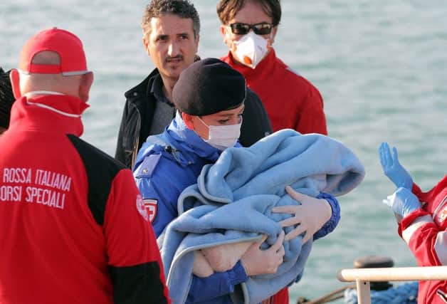 A Red Cross officer carries a baby to safety in Italy earlier this week. Picture: AP