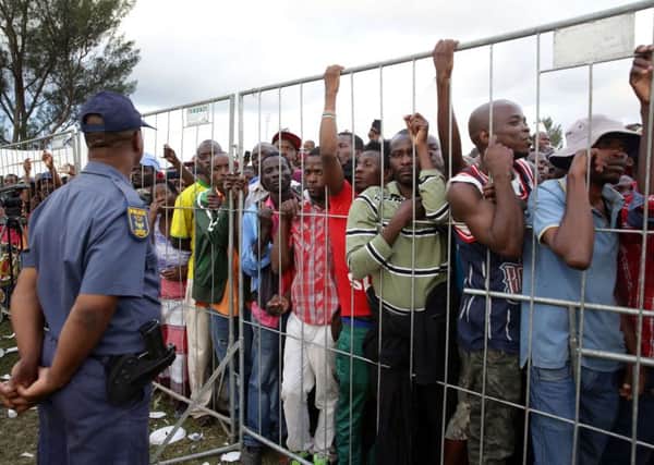 Police watch as hundreds of foreign nationals queue to listen to South African president Jacob Zuma at a temporary refugee camp in Chatsworth. Picture: Getty