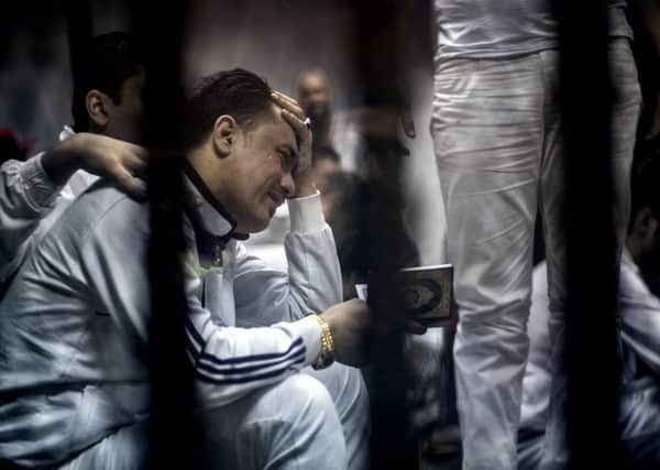 A defendant holds a Quran in a courtroom cage as a judge issues a verdict in a case involving violence by soccer fans in Port Said. Picture: AP