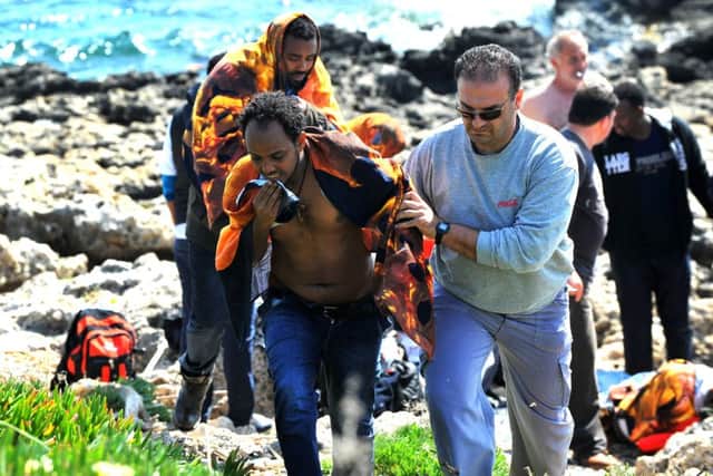 A Greek man helps a migrant to the shore yesterday after a boat ran aground. Picture: AP