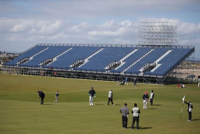 Golfers play on the 18th green as the grandstands are built for The Open golf tournament. Picture: PA
