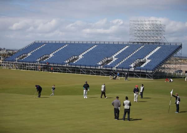 Golfers play on the 18th green as the grandstands are built for The Open golf tournament. Picture: PA
