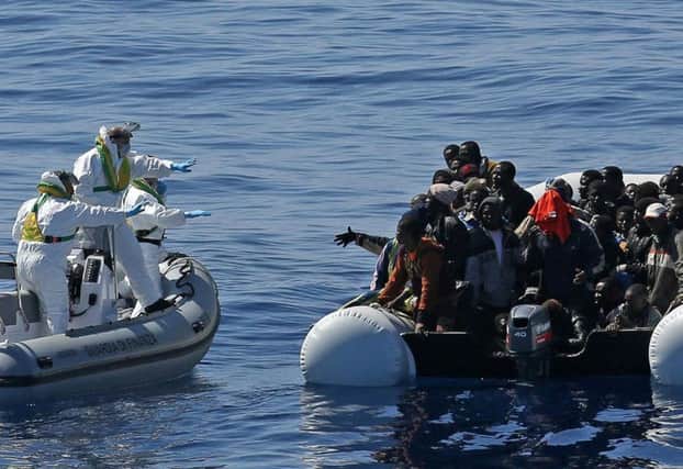 Italian Financial Police rescue unit approaches an inflatable dinghy crowded with migrants off the Libyan coast. Picture: AP