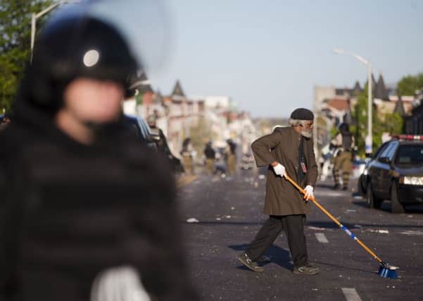 Residents clean streets as law enforcement officers stand guard in Baltimore. Picture: Getty