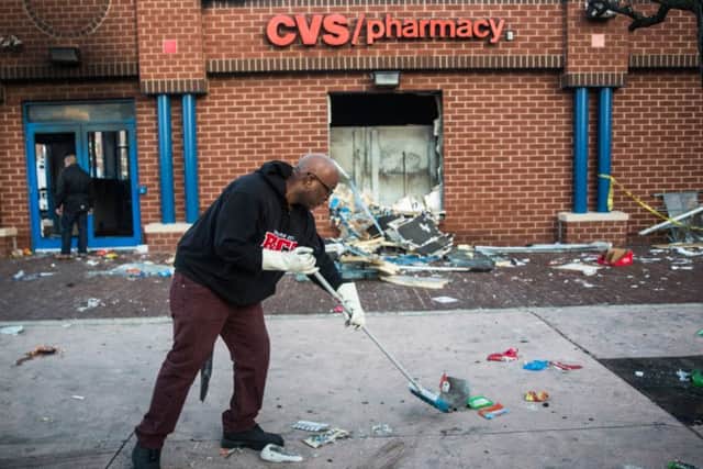 Jerald Miller helps clean up debris from a CVS pharmacy that was set on fire yesterday. Picture: Getty
