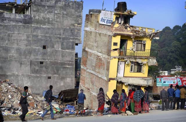 Bystanders in Kathmandu look at severely damaged flats left leaning precariously by the quake. Picture: AFP/Getty