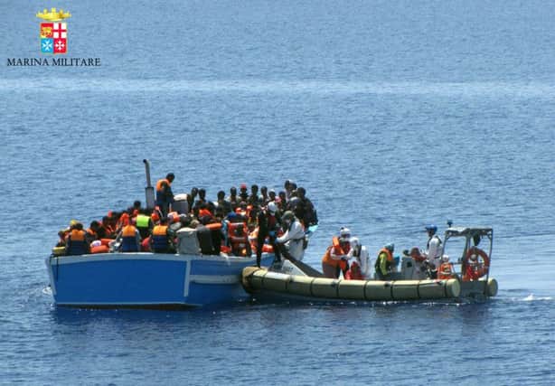 Sailors on an Italian navy dinghy pull alongside an overcrowded migrant boat to rescue passengers. Picture: AP