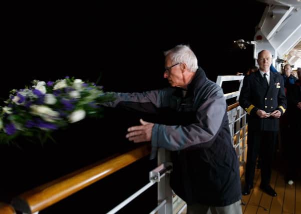 A passenger throws a wreath off of the Queen Victoria, as it takes part in a service to mark the 100th anniversary of the sinking of Lusitania. Picture: PA