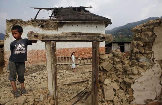 A child stands by the doorway of a damaged house in Nepal, where tens of thousands of homes have been demolished. Picture: AP